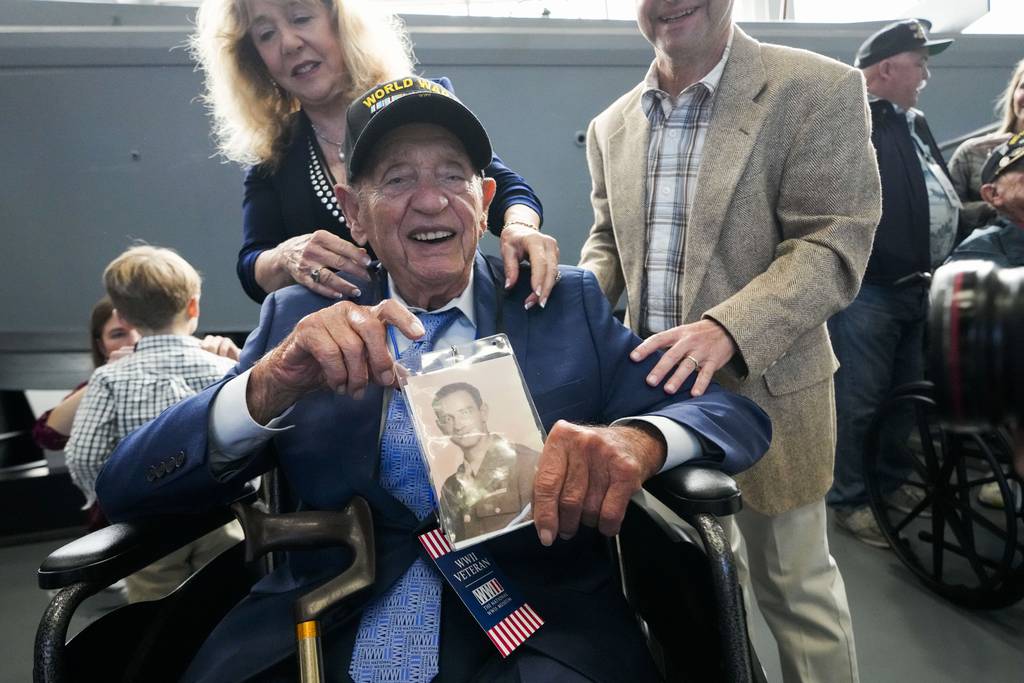 World War II veteran Joseph Eskenazi, who at 104 years and 11 months old is the oldest living veteran to survive the attack on Pearl Harbor, holds a photo of his younger self, at an event celebrating his upcoming 105th birthday at the National World War II Museum in New Orleans, Wednesday, Jan. 11, 2023.
