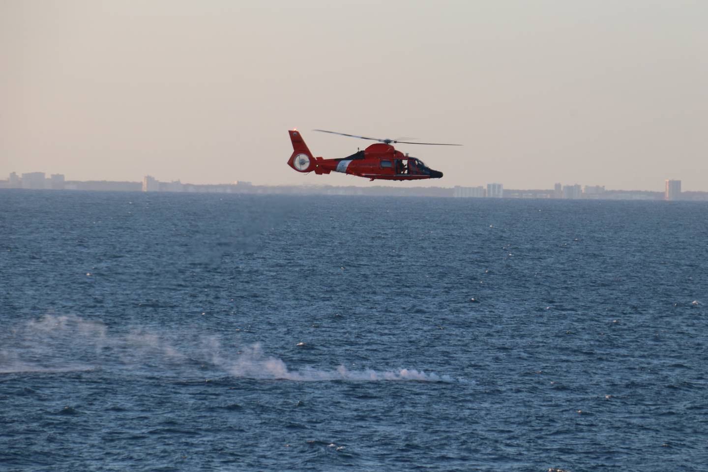 A Coast Guard helicopter flies over a debris field during recovery efforts of a high-altitude surveillance balloon Feb. 4, 2023.