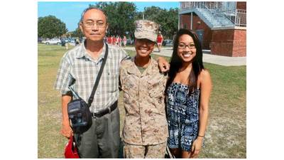 Ohu, center, stands with her father Ahr Yu, left, and sister Kay Yu after she earns the title of Marine.
