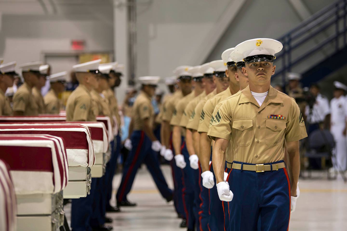 In this Wednesday, July 17, 2019 photo, Marines march past transfer cases carrying the possible remains of unidentified service members lost in the Battle of Tarawa during World War II in a hangar at Joint Base Pearl Harbor-Hickam in Hawaii.