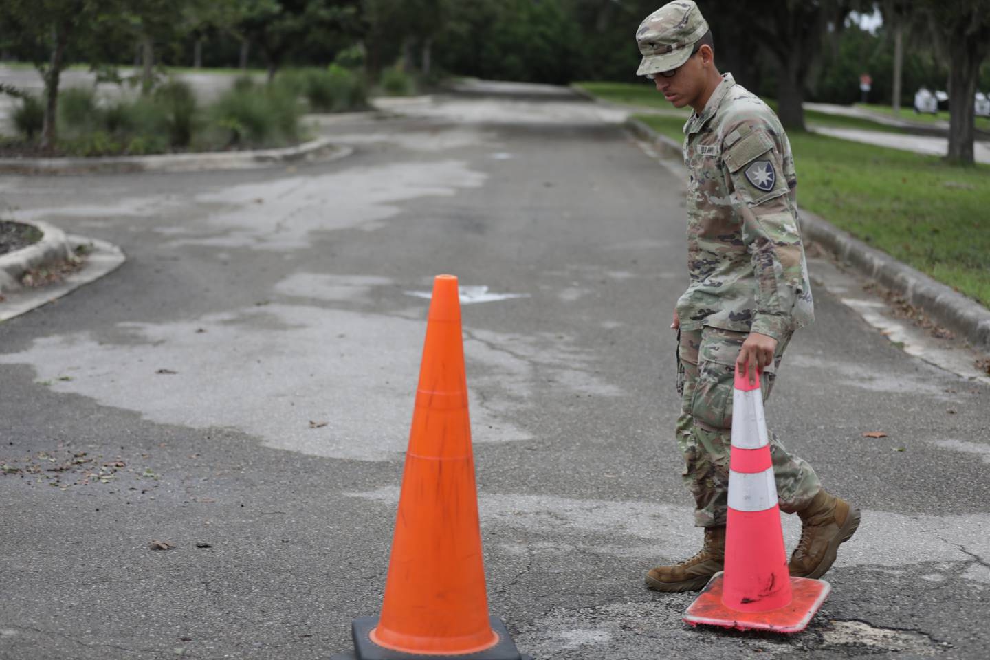 Spc. Anthony Correa, a soldier with the Florida National Guard's 50th Regional Support Group, sets up cones in preparation for the arrival of soldiers from other states' National Guards in Gainesville, Fla.