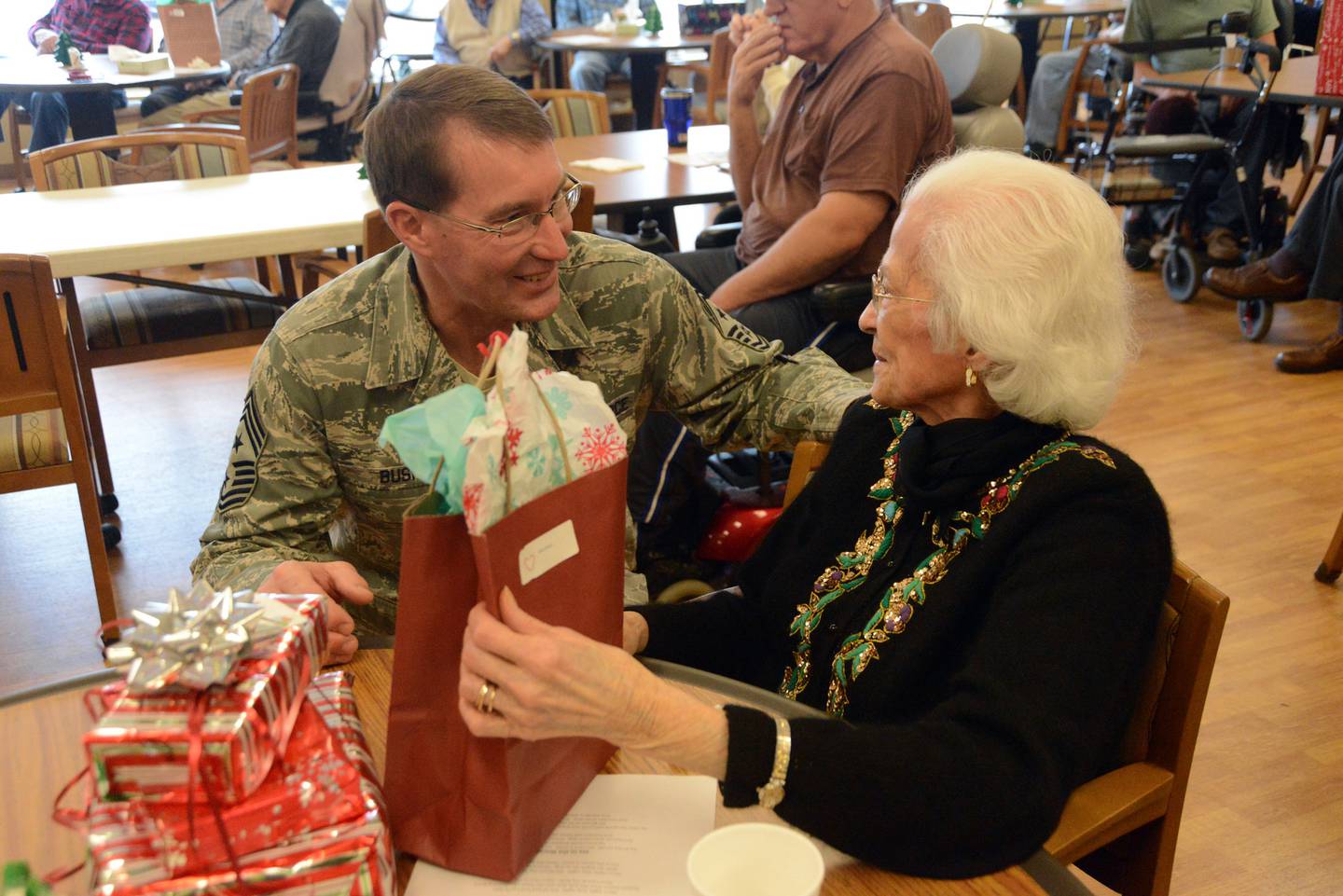 Air Force Chief Master Sgt. Ben Bush, the North Dakota National Guard State Command Chief, left, gives a gift and visits with a resident at the North Dakota Veterans Home in 2014, in Lisbon, North Dakota.