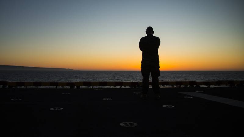 A Marine catches the sunrise before flight operations aboard the Wasp-class amphibious ship USS Essex, March 27, 2018.