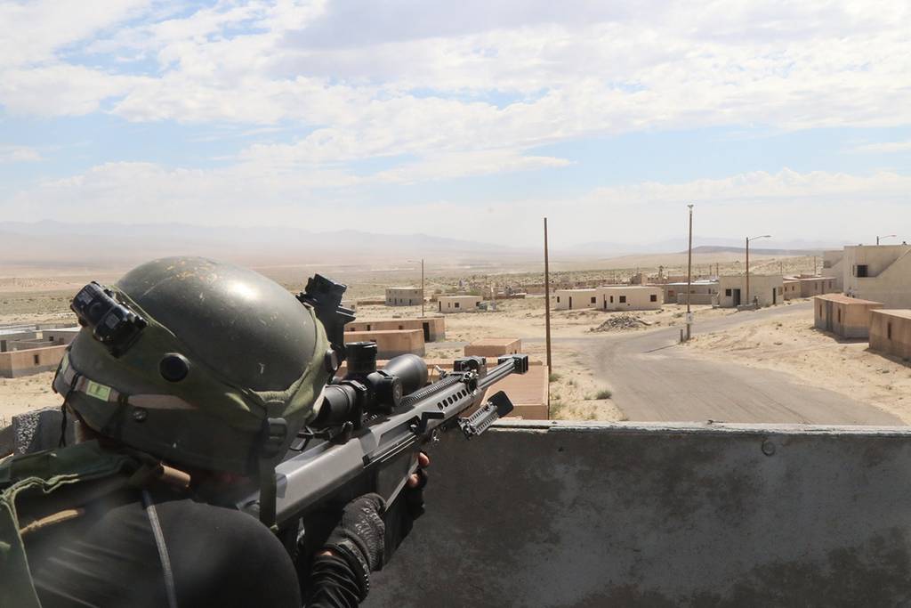 A soldier surveys the battlefield with a simulated Barrett M107 .50 caliber sniper rifle on July 12, 2019, in the city of Razish at the National Training Center at Fort Irwin, Calif.