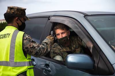 U.S. Marine Corps Lance Cpl. Aaron Santos conducts temperature checks on outbound traffic at Camp Courtney, Okinawa, Japan, July 13, 2020.