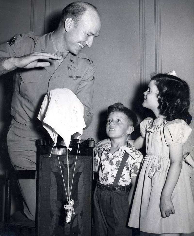 Col. Gail Halvorsen, the "Berlin Candy Bomber" demonstrates to two children how the candy parachutes work.