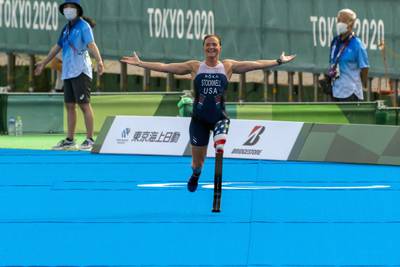 Paralympian Melissa Stockwell smiles and runs with her arms open to the finish line of the Women's Triathlon during the 2020 Tokyo Olympics.