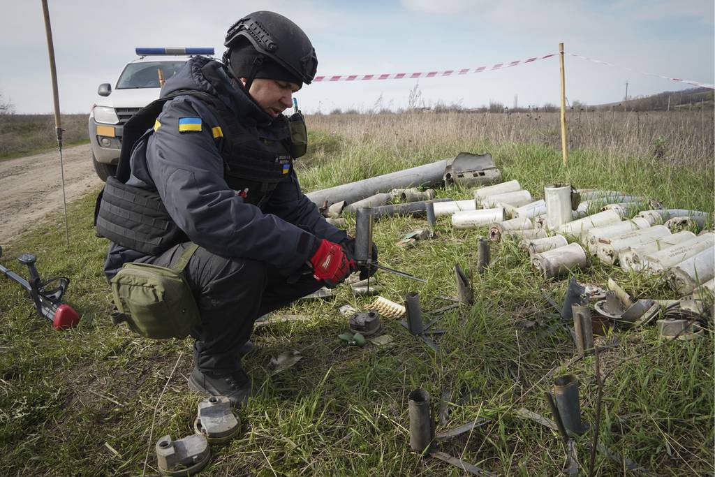 A sapper of the Ukrainian State Emergency Service collects remains of shells, grenades and other devices at the demining site near village of Kamenka, Kharkiv region, Ukraine, Tuesday, April 11, 2023.