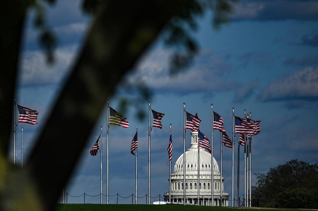 The dome of the U.S. Capitol building is seen behind a row of U.S. flags on April 10, 2020, in Washington.