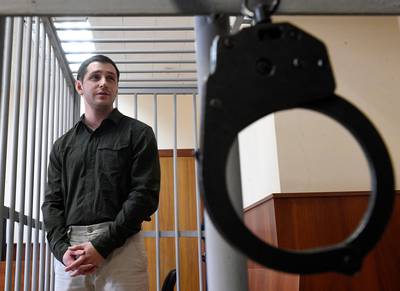 Marine Corps veteran Trevor Reed, charged with attacking police, stands inside a defendants' cage during a court hearing in Moscow on March 11, 2020.