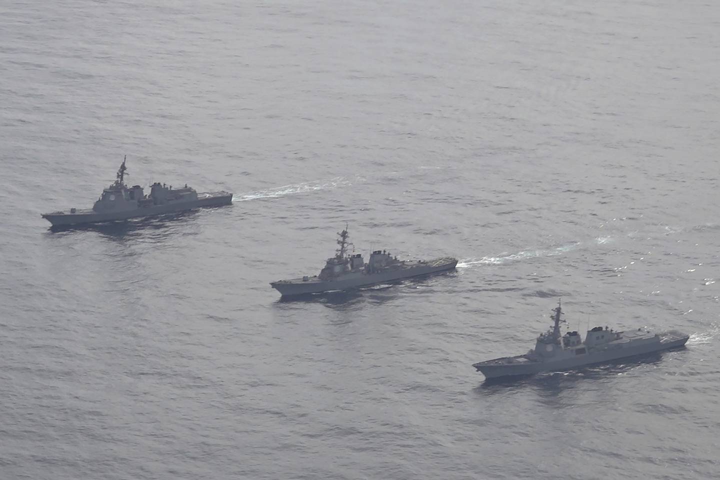 In this photo provided by South Korea Defense Ministry, Japan Maritime Self-Defense Force's destroyer Atago, left, U.S. Navy's Arleigh Burke-class guided-missile destroyer USS Barry, center, and South Korean Navy's Aegis destroyer King Sejong the Great, right, sail during a joint missile defense drill among South Korea, the United States and Japan in the international waters of the east coast of Korean peninsular, on Feb. 22, 2023.