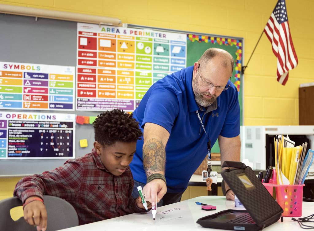 Retired Army veteran Christopher Simmons and E.C. teacher guides seventh-grader Elijah Williams through a math problem on Wednesday, Nov. 9, 2022, at Meadowlark Middle School in Winston-Salem, N.C.