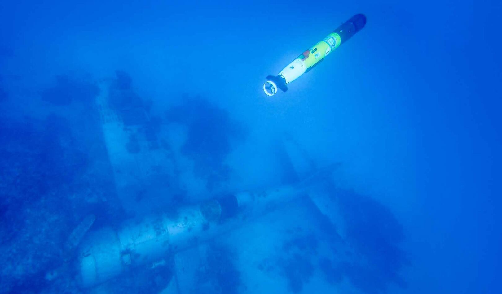 A REMUS Unmanned Underwater Vehicle (UUV) surveying a missing Corsair aircraft in the western lagoon of the Republic of Palau. The UUV is equipped with side scan sonar to allow for mapping of the seabed even in poor water visibility, with variants of the same robotic technology in use by the US Navy. Subsequent forensic analysis of the Corsair by Project Recover found the data plates of the aircraft. Research of historical war records determined the plane was based from VMF-122 and shot down Nov. 21, 1944; the pilot safely escaped, swam outside the lagoon, and was recovered by a rescue seaplane from his squadron.