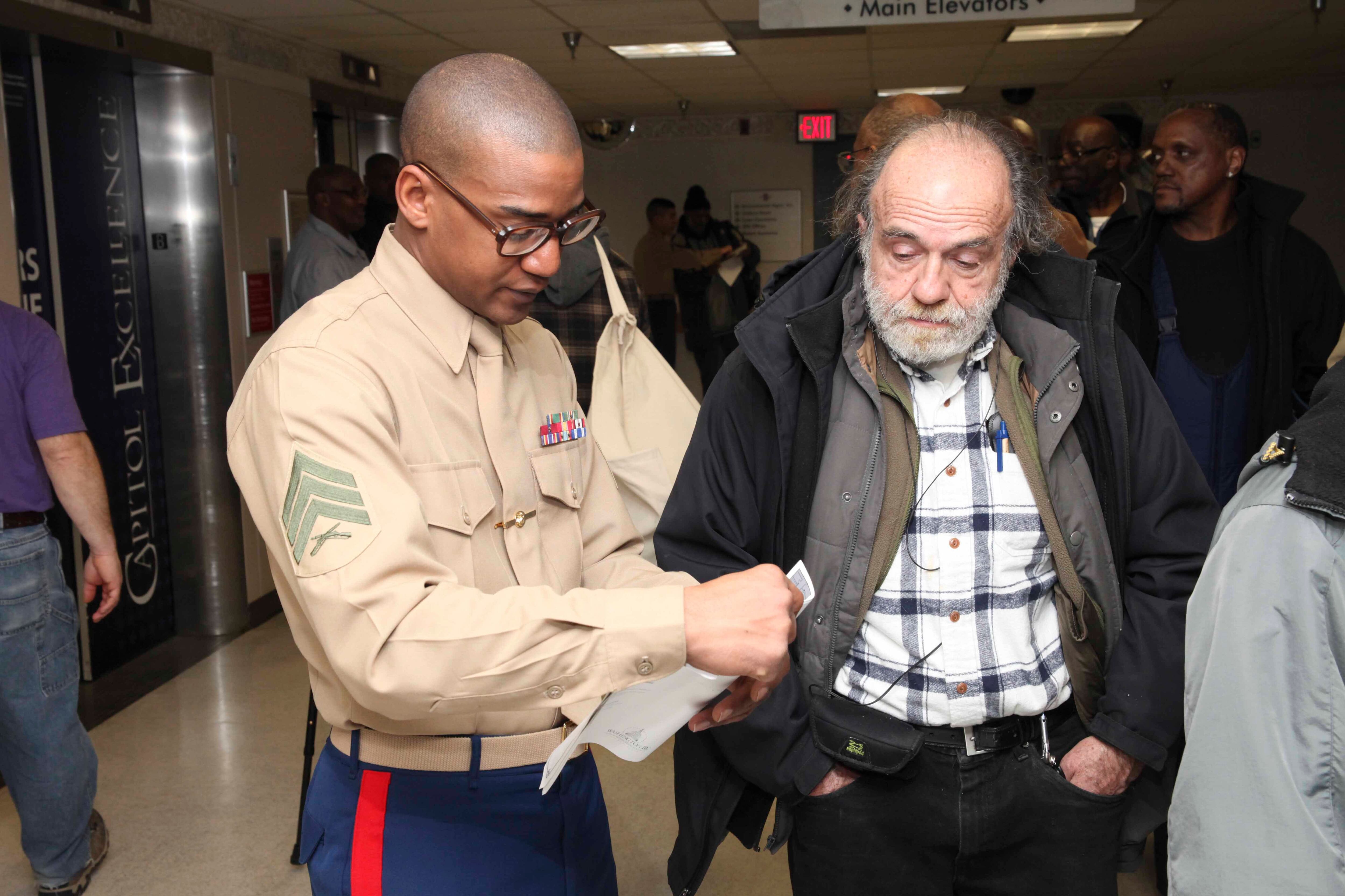 Marine Corps Sgt. David E. Martin assists a veteran during his visit to the Veterans Affairs Medical Center in Washington, D.C., in 2014, during an event for unhoused veterans.