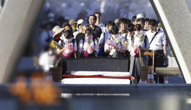 Visitors pay in front of the cenotaph dedicated to the victims of the atomic bombing at the Hiroshima Peace Memorial Park in Hiroshima, western Japan Sunday, Aug. 6, 2023.