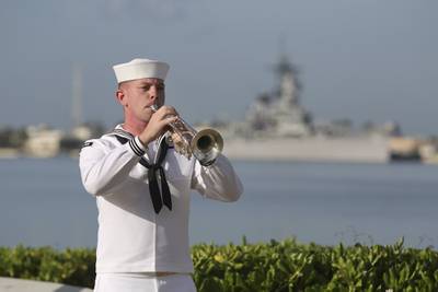 A U.S. Navy sailor plays "Taps" in front of the USS Missouri during a ceremony to mark the anniversary of the attack on Pearl Harbor, Monday, Dec. 7, 2020, in Pearl Harbor, Hawaii.